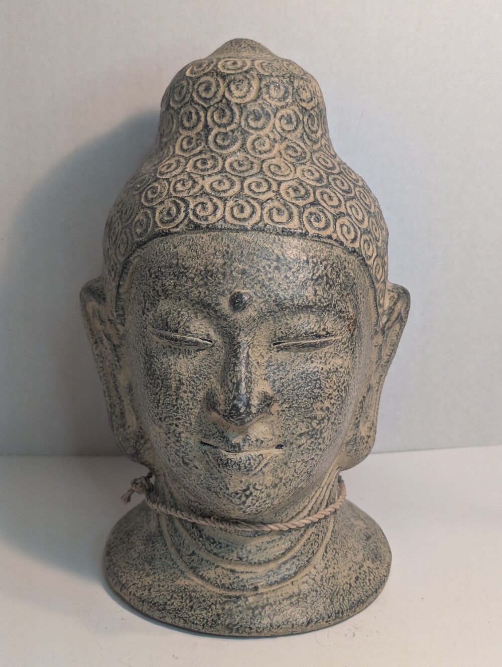 Buddha head statue featuring a tan gold, gray texture and intricate coiled hair.